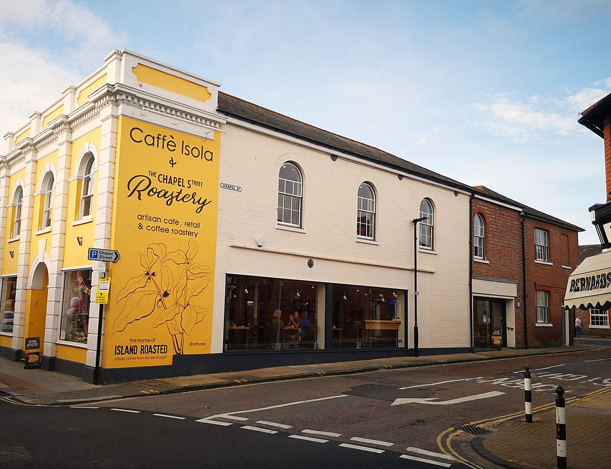 Caffe Isola's yellow-painted corner building on St James' Street, with the roastery sign on its side