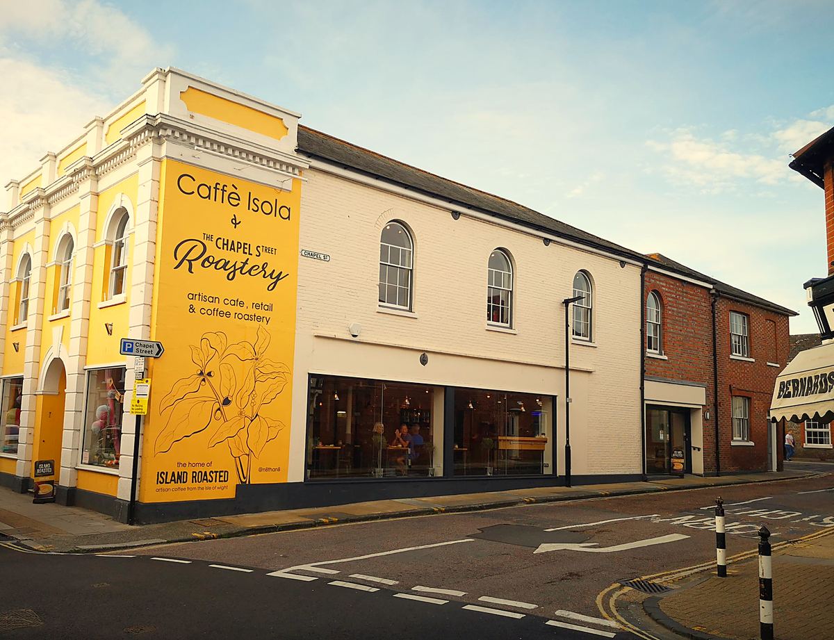 Caffe Isola's yellow-painted corner building on St James' Street, with the roastery sign on its side